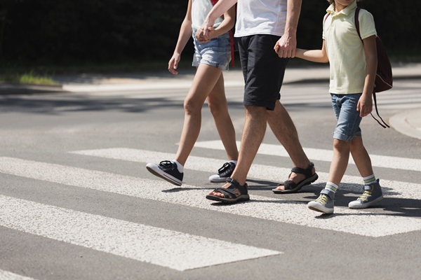 Father holding hands with his kids while on pedestrian crossing.